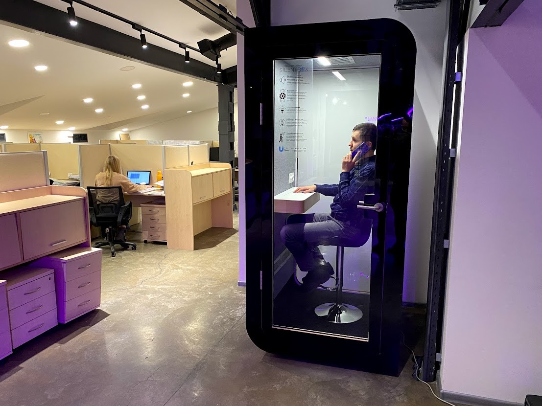 Pracownik prowadzący rozmowę telefoniczną wewnątrz kabiny akustycznej